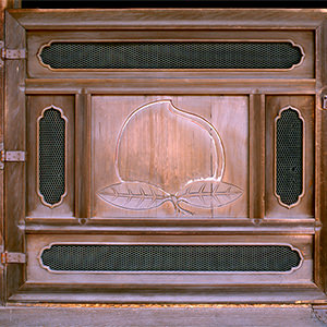 <b>桃戸</b>正面入口には桃戸と呼ばれる半扉があり、その板には魔除けとされる桃の実の彫刻が施されています。
